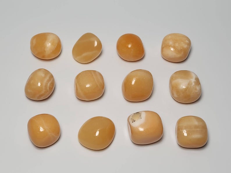 May include: Twelve tumbled orange calcite stones with white veining. The stones are smooth and polished.