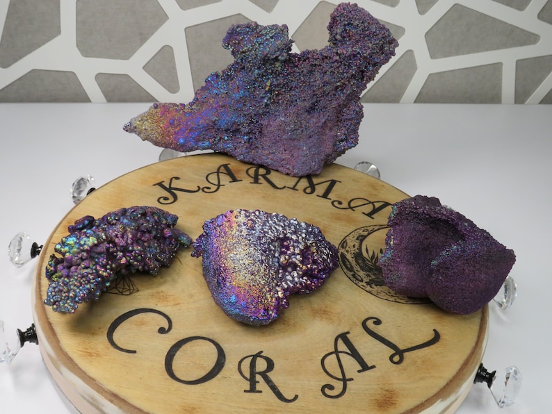 May include: Four iridescent purple and blue gemstone clusters on a wooden base with the words "Karma Coral" engraved on it.