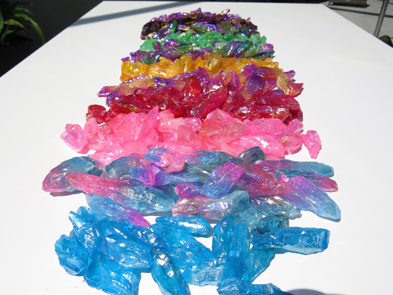 May include: A rainbow assortment of iridescent crystal points. The crystals are arranged in a rainbow order, starting with purple and ending with blue.