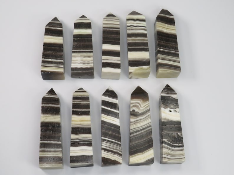 May include: Twelve black and white striped obelisk shaped crystal points. The points are approximately 2 inches in length.