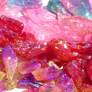 May include: A collection of iridescent quartz crystals in various shades of pink, red, and purple. The crystals are raw and have a natural, rough texture.