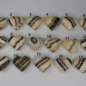 May include: Seventeen heart-shaped polished stones with black and white stripes. The stones are numbered 1 through 17.