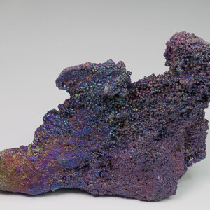 May include: A large, iridescent, purple and blue goethite specimen with a rough, textured surface. The mineral has a unique, bubbly appearance.
