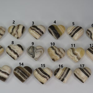 May include: A set of 17 heart-shaped polished stones with brown and white stripes. The stones are numbered 1 through 17.