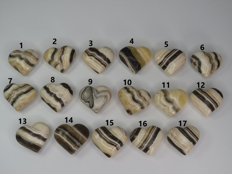 May include: A set of 17 heart-shaped polished stones with brown and white stripes. The stones are numbered 1 through 17.