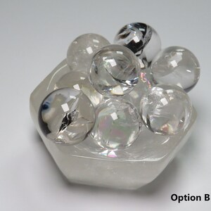 May include: A cluster of clear quartz crystal spheres in a hexagonal clear quartz crystal bowl. Option B.