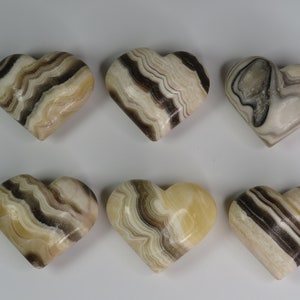May include: Six heart-shaped stones with brown and white striped patterns. The stones are polished and smooth.