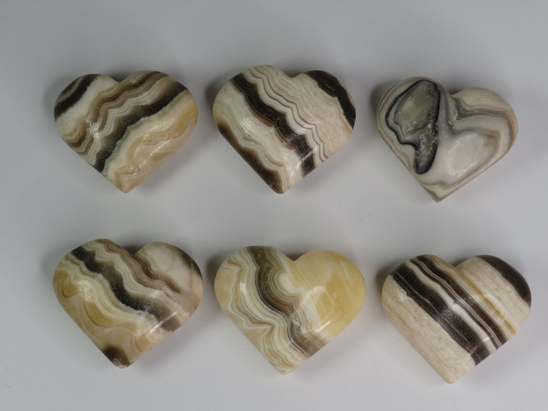 May include: Six heart-shaped stones with brown and white striped patterns. The stones are polished and smooth.
