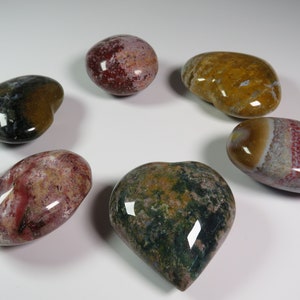 May include: Six heart-shaped polished stones with various patterns and colours, including red, green, brown, and white.
