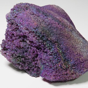 May include: A large, purple, iridescent agate with a rough, textured surface. The agate has a bubbly, bumpy texture and is a beautiful example of this type of gemstone.