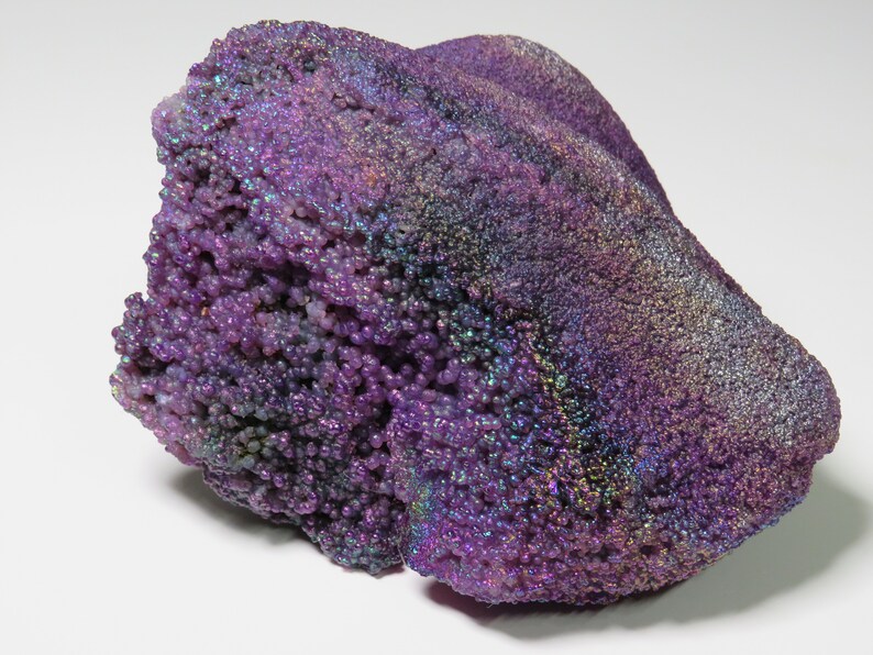 May include: A large, purple, iridescent agate with a rough, textured surface. The agate has a bubbly, bumpy texture and is a beautiful example of this type of gemstone.