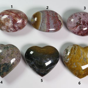 May include: Six polished heart-shaped and oval-shaped stones with various patterns of red, white, brown, yellow, and green. The stones are numbered 1 through 6.