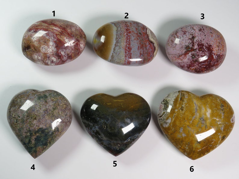 May include: Six polished heart-shaped and oval-shaped stones with various patterns of red, white, brown, yellow, and green. The stones are numbered 1 through 6.