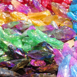 May include: A collection of iridescent crystal points in various colours, including red, orange, yellow, green, blue, and purple. The crystals are arranged in a rainbow pattern.