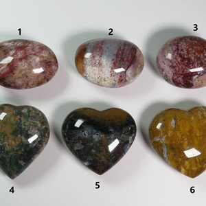 May include: Six polished heart-shaped and oval-shaped stones with various patterns of red, white, brown, green, and yellow. The stones are numbered 1 through 6.