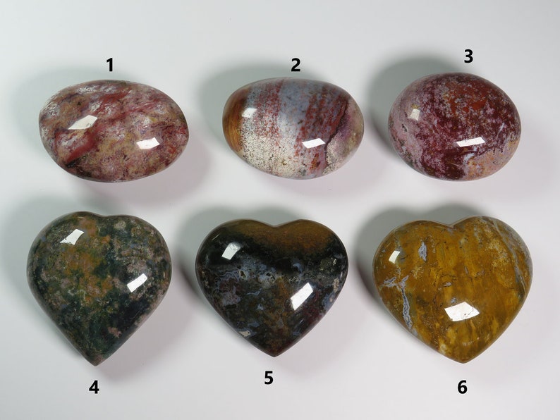 May include: Six polished heart-shaped and oval-shaped stones with various patterns of red, white, brown, green, and yellow. The stones are numbered 1 through 6.