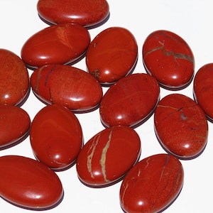 May include: A collection of smooth, polished red jasper stones, each with unique patterns and striations. The stones are oval-shaped and have a glossy finish.