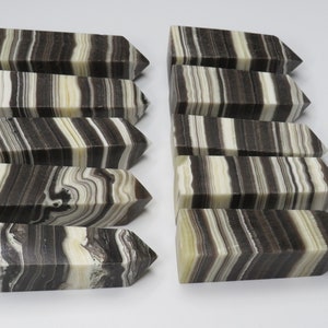 May include: Ten black and white striped onyx crystal points. The points are polished and have a smooth, glossy finish. The stripes are natural and vary in width and color.