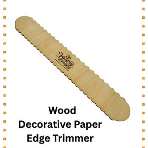 May include: A light-colored wooden paper edge trimmer featuring a scalloped edge design along both sides. The center of the tool is branded with the text Valenz Designz. The object is presented against a white background with a border of orange squares.