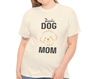 Può includere: T-shirt color crema con le parole "Doodle DOG MOM" in nero e una grafica di cane doodle dorato. La maglietta ha una trama maculata ed è indossata da una persona.