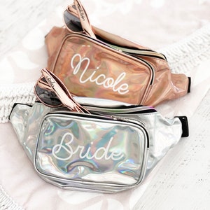Top fanny pack is rose gold with the name Nicole and the bottom fanny pack is silver with the text Bride