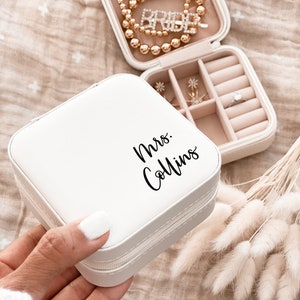 A small white faux leather jewelry box printed with Mrs. in black script text.