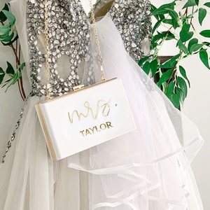 White purse hanging in front of a sparkly white dress