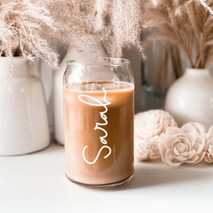 Can-shaped glass cup filled with iced coffee.