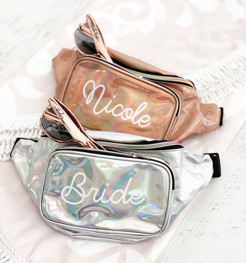 Top fanny pack is rose gold with the name Nicole and the bottom fanny pack is silver with the text Bride
