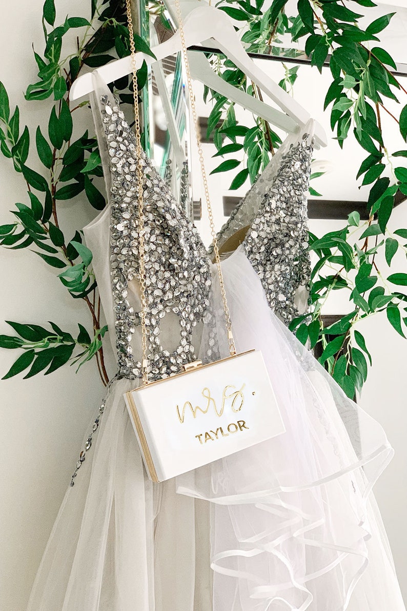 White purse hanging in front of a sparkly white dress