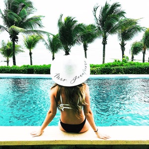 girl wearing white sun hat with black vinyl text