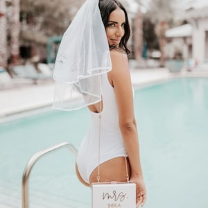 Girl holding a white purse in front of a pool