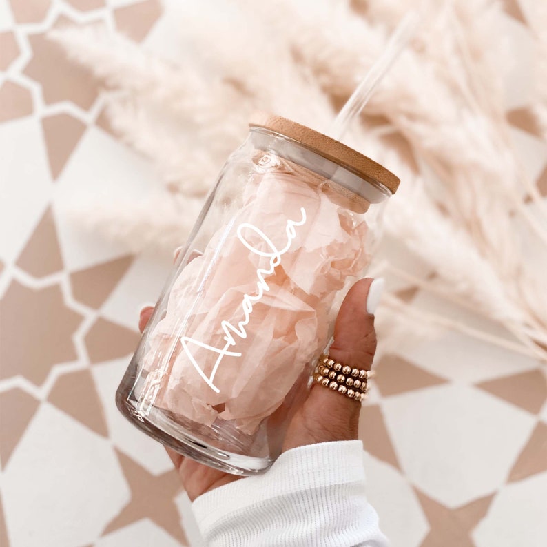 Clear glass iced coffee cup with a bamboo lid, clear straw, and printed with a custom name in white script text.