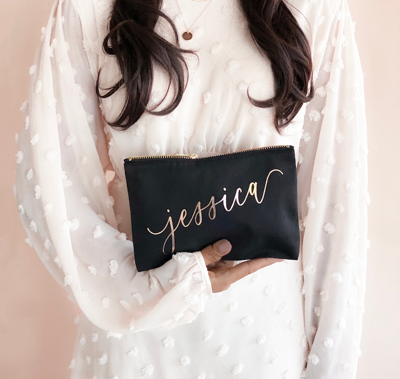 Women in white dress holding a black bag with rose gold name