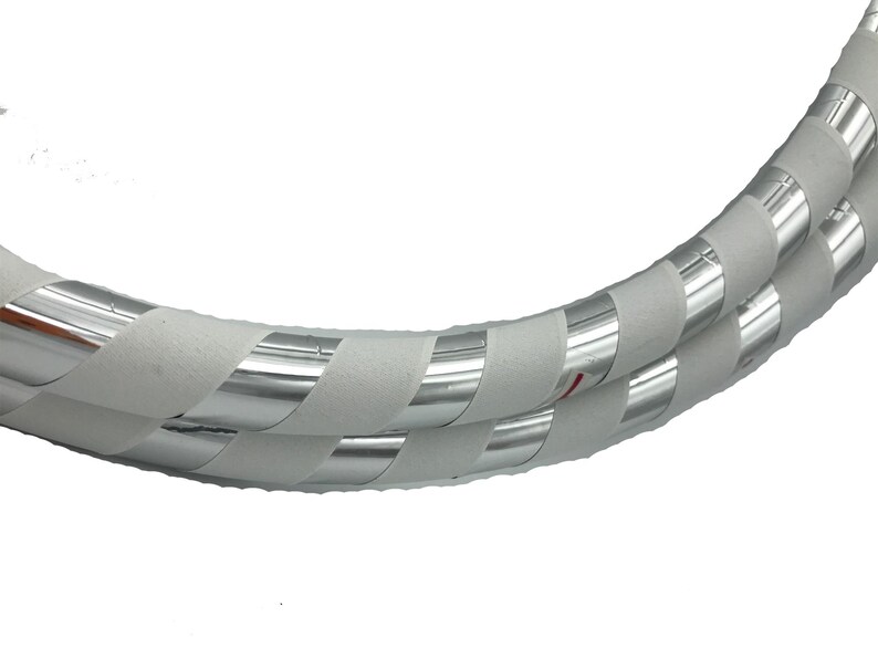 K&ouml;nnte beinhalten: Ein wei&szlig;er und silberner Reifen mit einer strukturierten Oberfl&auml;che. Der Reifen besteht aus zwei Rohrst&uuml;cken, die mit wei&szlig;em Klebeband und silbernem reflektierendem Klebeband umwickelt sind.