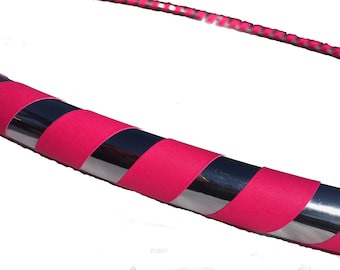 Könnte beinhalten: Ein rosa-silberner Fitnessreifen mit einem gestreiften Muster. Der Reifen ist aus Metall und hat eine gepolsterte Ummantelung.