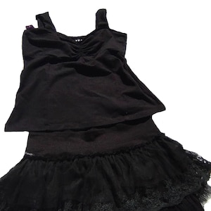 May include: A black tank top with a ruffled neckline and a black tulle skirt with lace trim.
