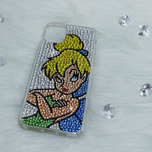 Könnte beinhalten: Transparente Handyhülle mit silbernen, gelben, grünen, blauen und bronzefarbenen Strasssteinen verziert. Das Design zeigt eine Cartoon-Fee mit gelbem Haar und einer blauen Schleife. Die Hülle ist mit funkelnden Strasssteinen verziert.