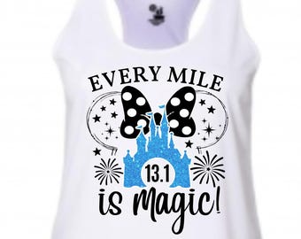 May include: White racerback tank top with the text "Every Mile is Magic!" in black script. The design includes a black polka dot bow, a blue castle, and fireworks. The number "13.1" is in the castle.