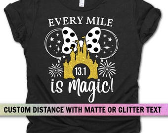 Może przedstawiać: Czarny t-shirt z białą i złotą grafiką. Grafika zawiera zamek, kokardę w kropki i napis "Every Mile is Magic!" z "13.1" pośrodku. Na dole koszulki znajduje się napis "CUSTOM DISTANCE WITH MATTE OR GLITTER TEXT".