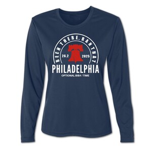 Op de afbeelding: Marineblauwe longsleeve met een wit en rode afbeelding. De afbeelding bevat de tekst "Been There, Ran That" rond een Liberty Bell-afbeelding, met "26.2" en "2025" erin. Het woord "Philadelphia" wordt ook weergegeven.