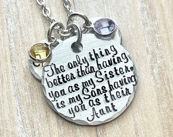 Puede incluir: Collar de plata con un dije redondo que dice "Lo único mejor que tenerte como hermana es que mis hijos te tengan como tía". El dije tiene tres pequeñas piedras preciosas: amarilla, morada y transparente.