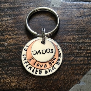 May include: Silver key chain with a layered charm that reads "To infinity and beyond, Daddy I love you".