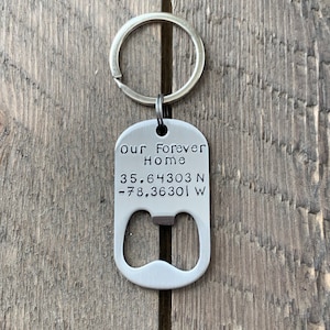 Könnte beinhalten: Silberner Schlüsselanhänger mit einem Flaschenöffner und graviertem Text "Our Forever Home 35.64303 N -78.36301 W".