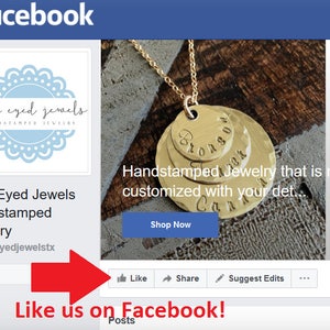May include: A Facebook page for Blue Eyed Jewels, a business that makes hand-stamped jewelry. The page features a photo of a gold necklace with three hand-stamped discs. The text "Handstamped Jewelry that is made just for you, customized with your details..." is visible below the photo. The text "Shop Now" is on a blue button. The page also includes a "Like" button, a "Share" button, and a "Suggest Edits" button.