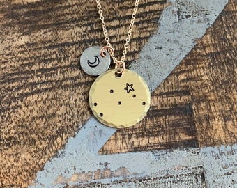 Può includere: Collana d'oro con un ciondolo rotondo martellato che presenta un designo di costellazione con una piccola stella e un piccolo ciondolo a forma di mezzaluna.