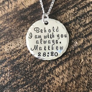 May include: Silver necklace with a round pendant that reads "Behold I am with you always. Matthew 28:20".