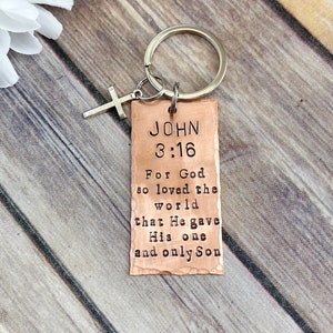 Könnte beinhalten: Kupfer-Schlüsselanhänger mit einem silbernen Kreuz-Anhänger und einem Anhänger mit der Aufschrift "JOHN 3:16 For God so loved the world that He gave His one and only Son".