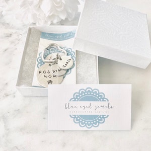 May include: A silver keychain with three charms. The charms are round and have the words "Rosie", "Brew", and "Fos Mom" engraved on them. The keychain is in a white box with a blue and white card that says "blue eyed jewels handstamped jewellery".