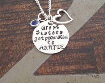 Puede incluir: Collar de plata con un dije en forma de corazón y un dije redondo que dice "Great Sisters get promoted to AUNTIE". Una piedra preciosa azul está unida a la cadena.